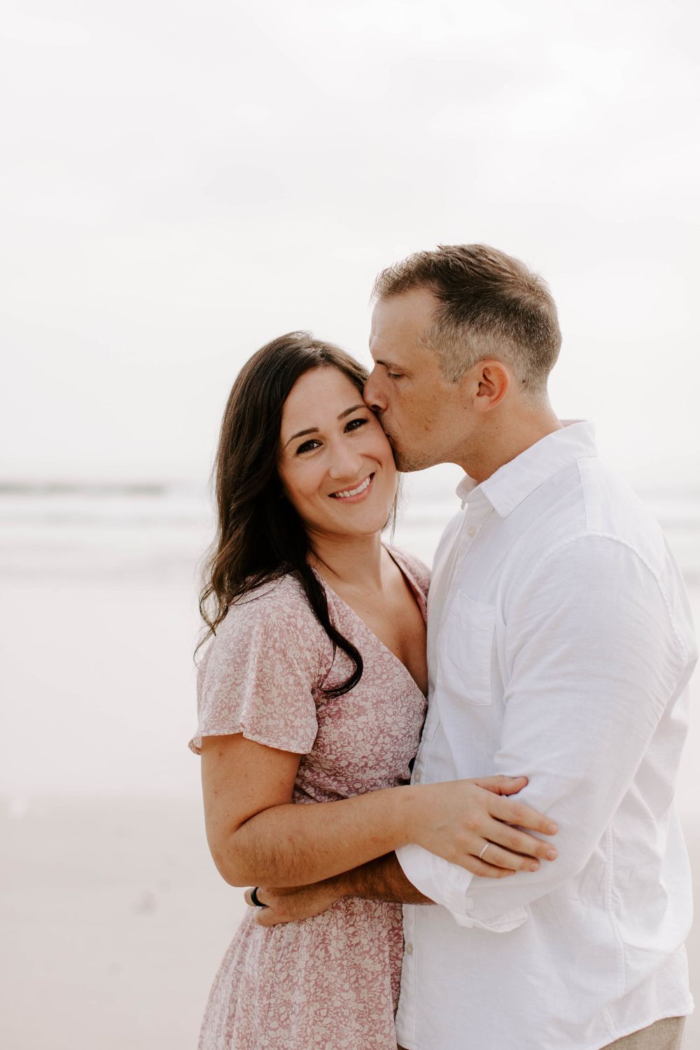 Romantic couple shares intimate moments in soft lighting on beach.