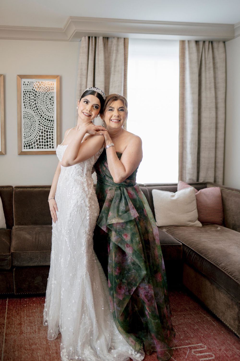 People in formal attire share joyful laughs in an elegant room with modern wall art and neutral decor.