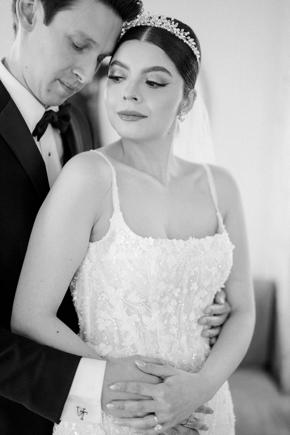 Black and white intimate wedding portrait showing bride in beaded spaghetti strap gown and crystal tiara with groom in tuxedo.