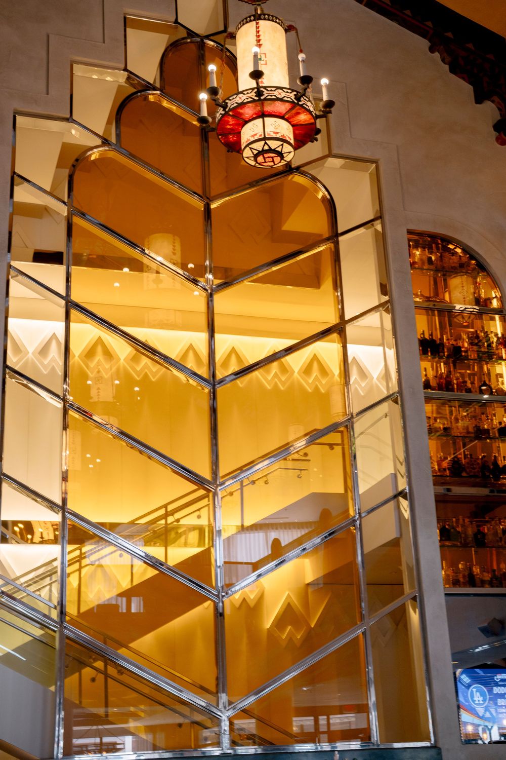 Elegant wooden staircase illuminated by warm lighting in modern interior with geometric glass panels and metallic railings.