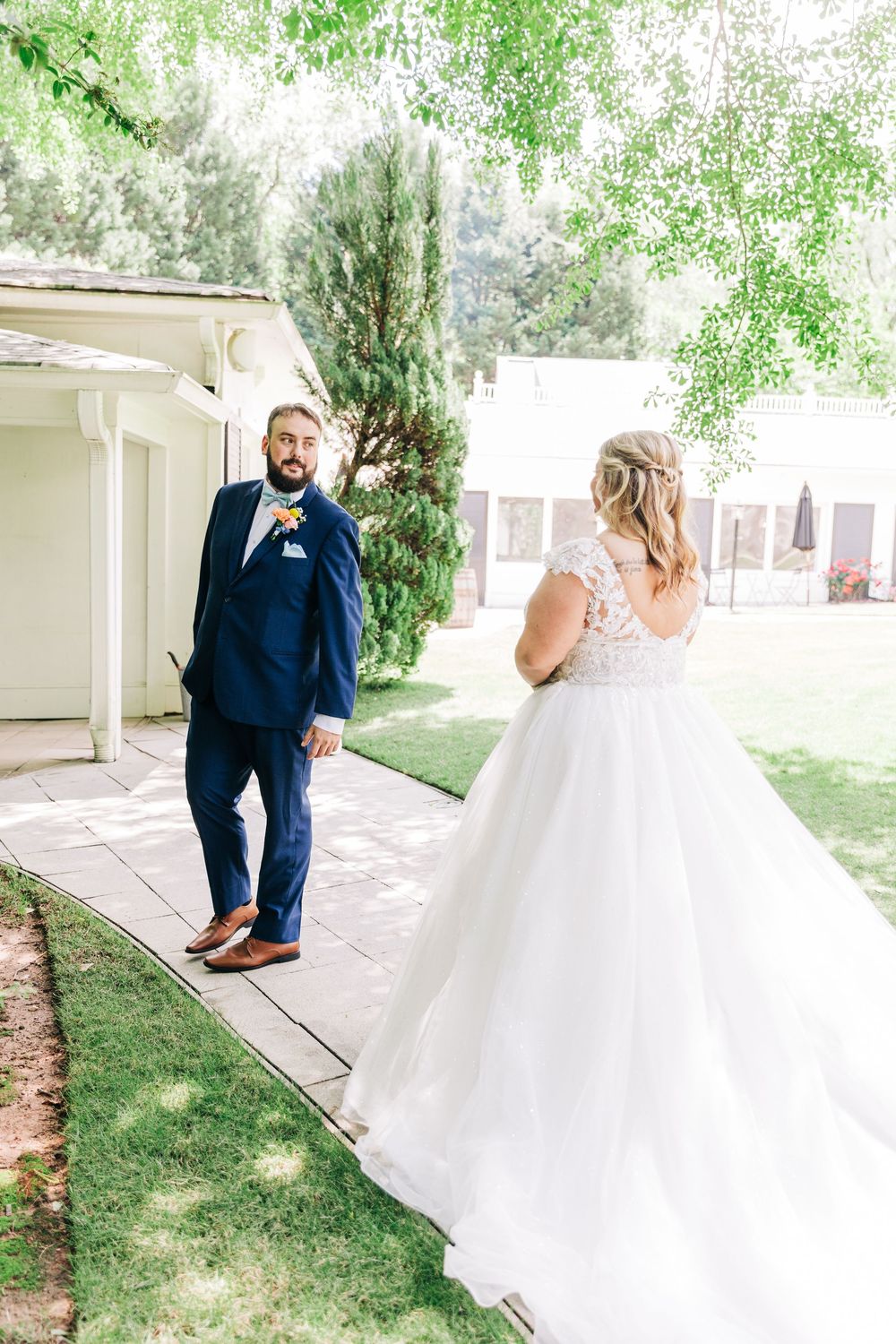 A first look moment between bride and groom in formal attire captured in a backyard setting with natural lighting.