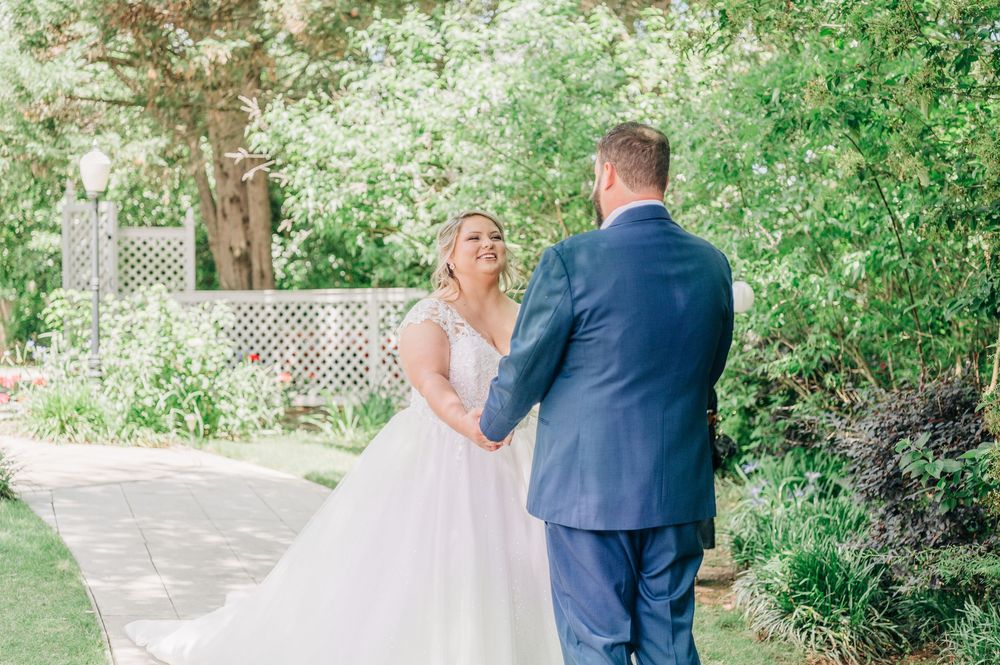 A romantic wedding scene with a couple sharing a moment outside in a lush green garden setting.
