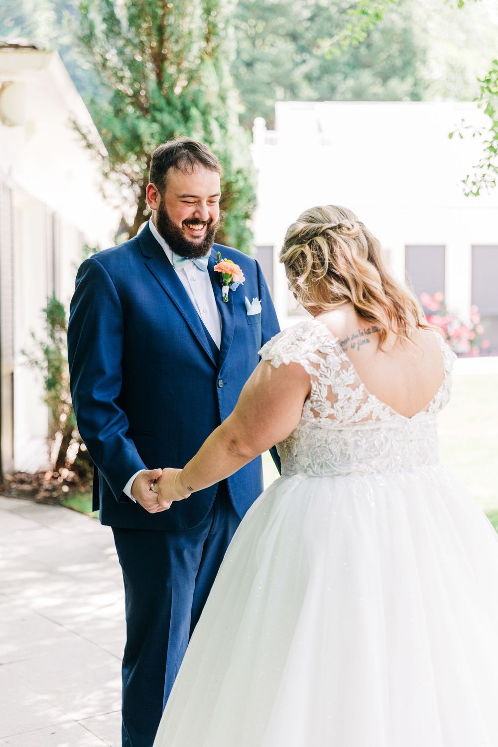 A couple shares an emotional first look moment during their wedding, with the bride in white and groom in navy blue.