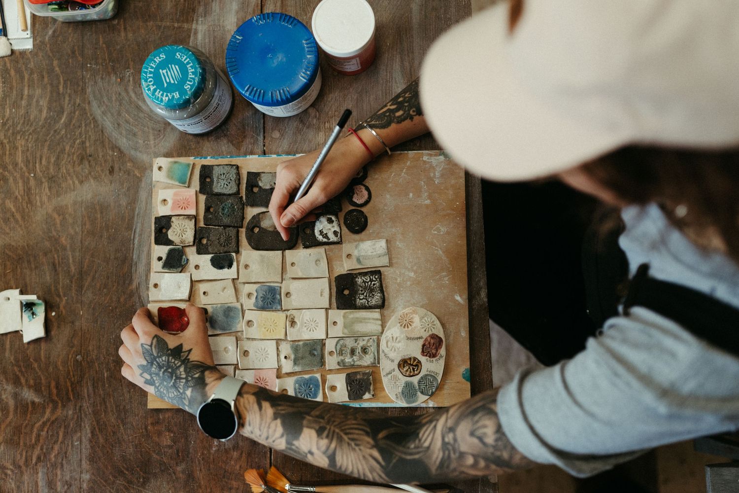 Overhead view of someone mixing shades of blue paint on a square ceramic palette.