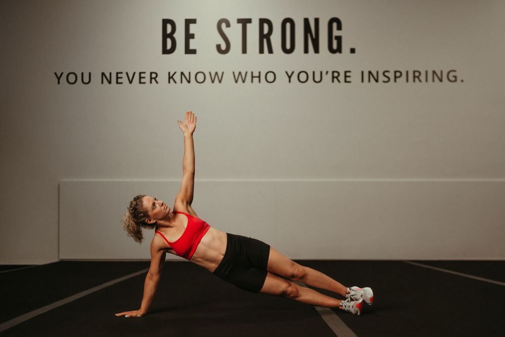 Motivational fitness quote 'BE STRONG' displayed alongside silhouettes of people exercising in a gym setting.