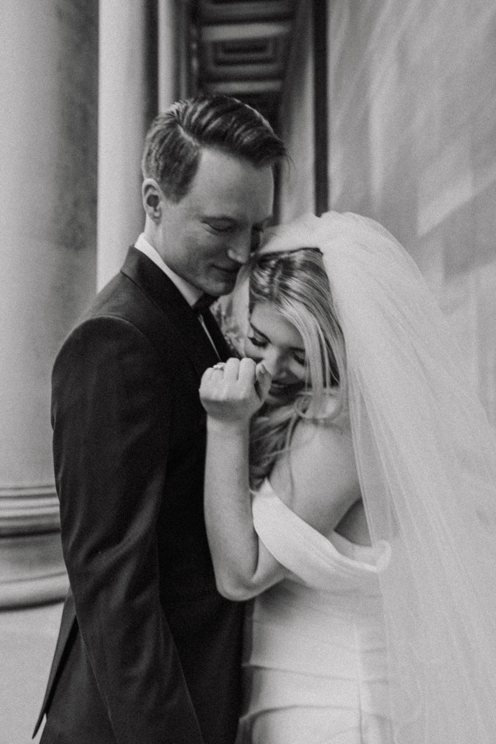 A tender black and white wedding photo showing a couple sharing an intimate moment, with the bride in white and groom in black.