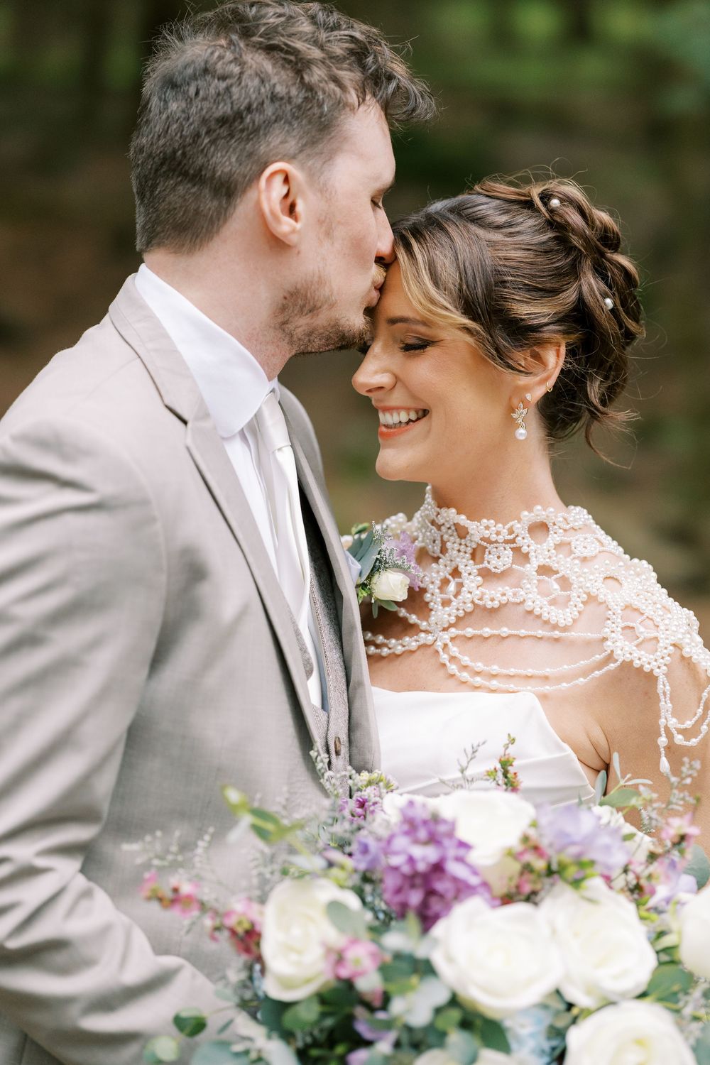 Romantic wedding moment outdoors with delicate lace details and vibrant purple and white floral bouquet at Windham Manor.