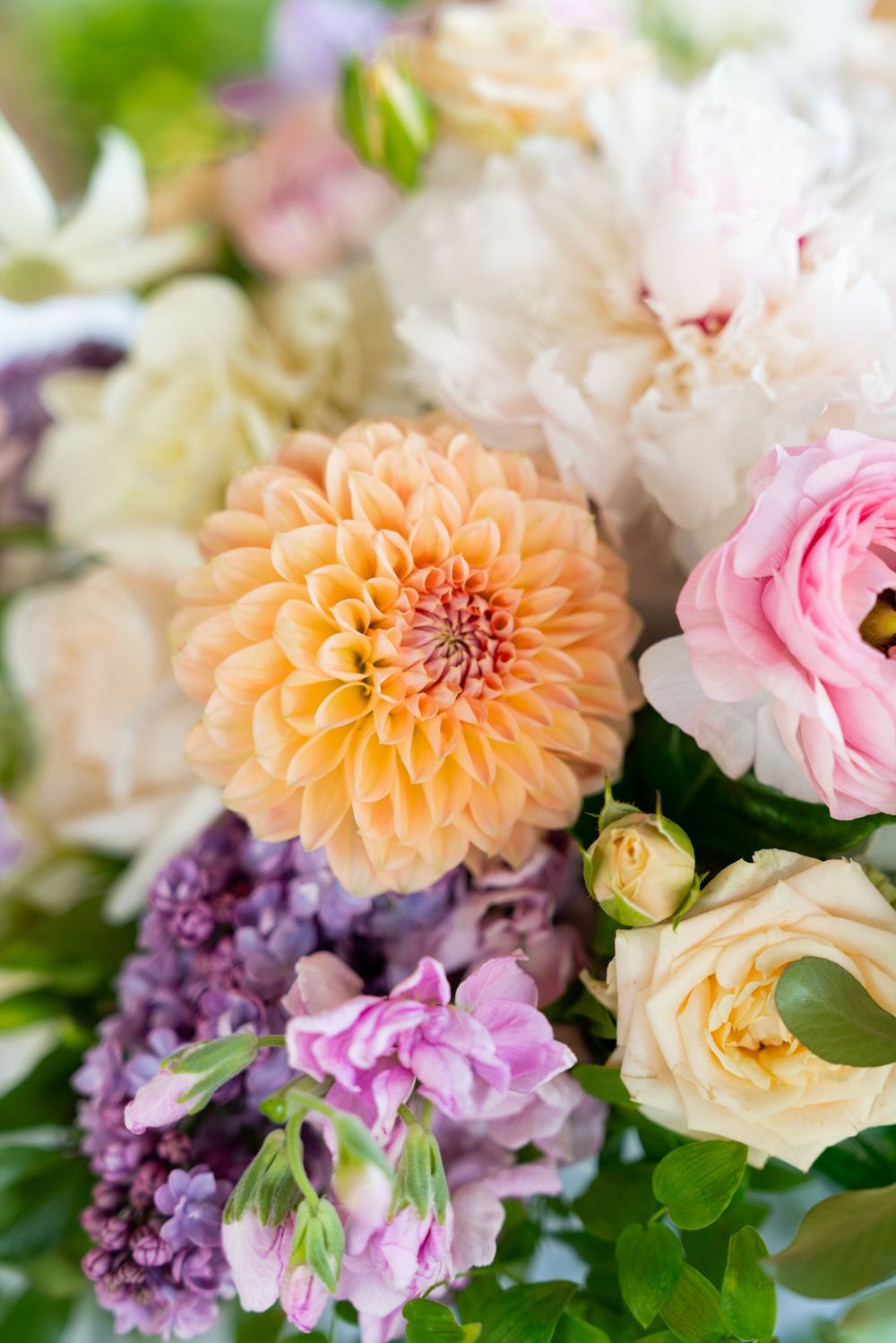 Close up of pastel dahlia, roses and other flowers in a romantic garden-style floral arrangement.