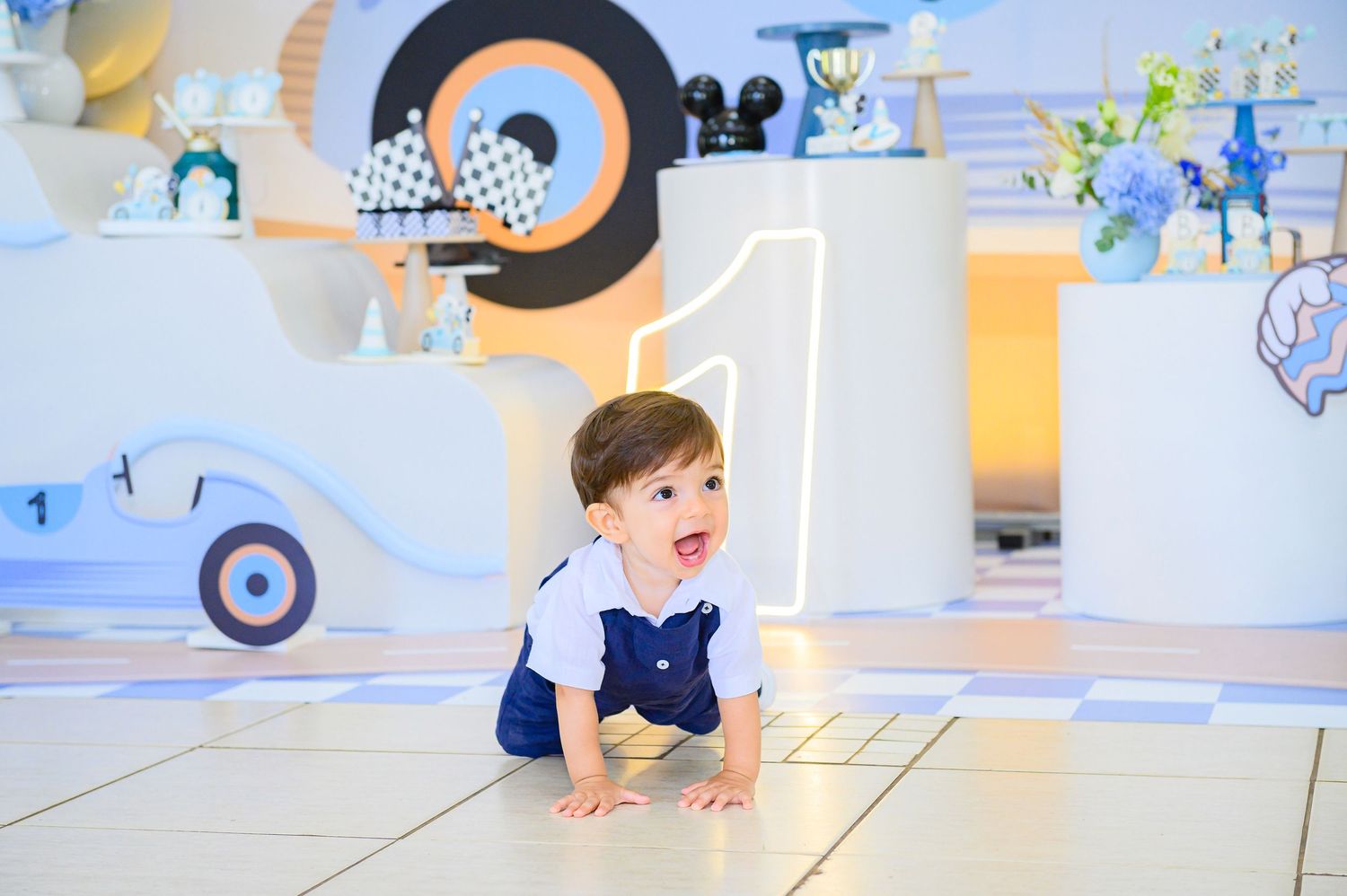 A toddler crawls on a white floor in a playful environment decorated with colorful wall murals and artistic elements.