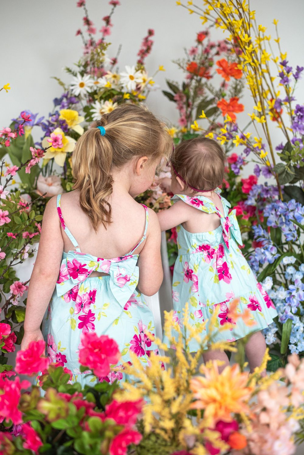 Two figures in matching floral dresses admire a vibrant garden of colorful summer flowers. Taken at Studio 428 in Leesburg Va