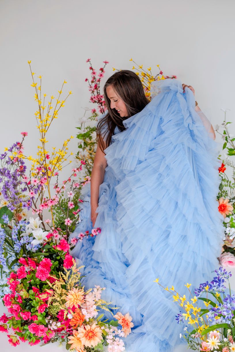 Ethereal light blue tulle gown surrounded by vibrant spring flowers including pink, yellow and purple blooms.