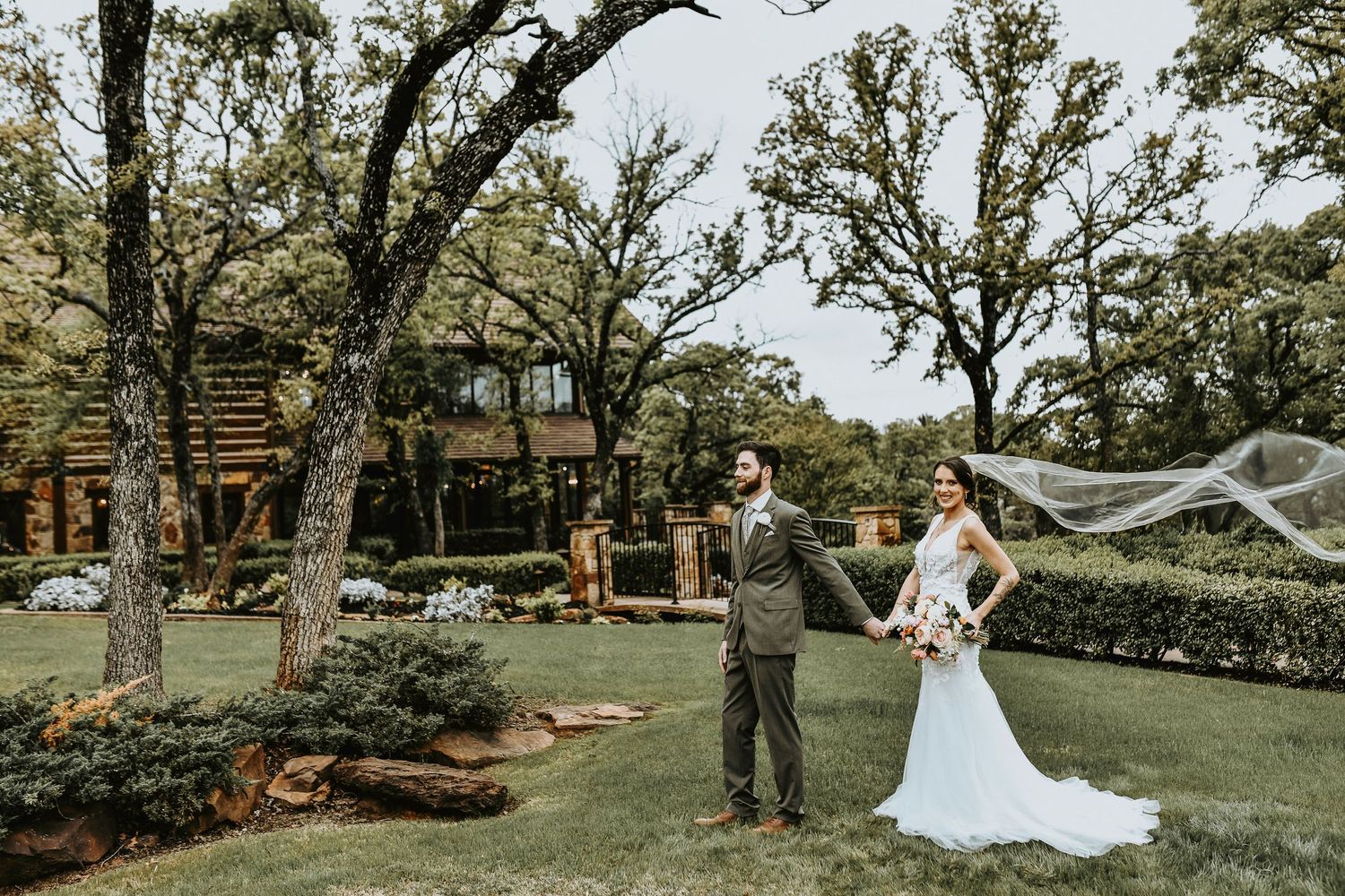 Bride and groom sharing an intimate moment on the garden bridge at The Lodge, with soft greenery and flowers surrounding them.