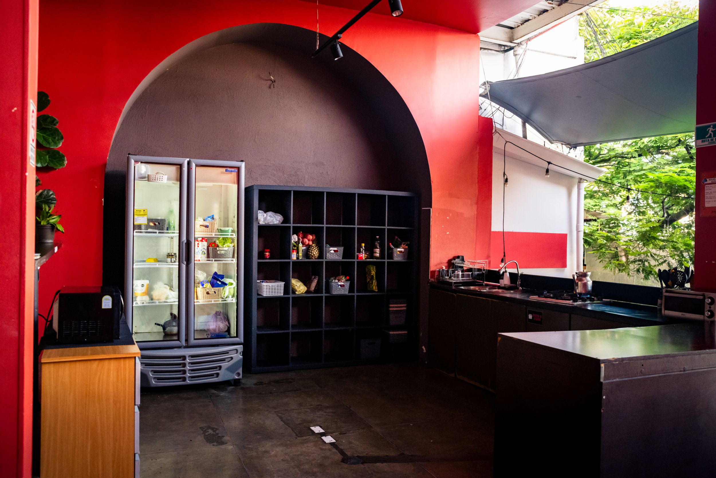 A modern commercial kitchen interior with red painted walls, black countertops and glass refrigerator display cases.