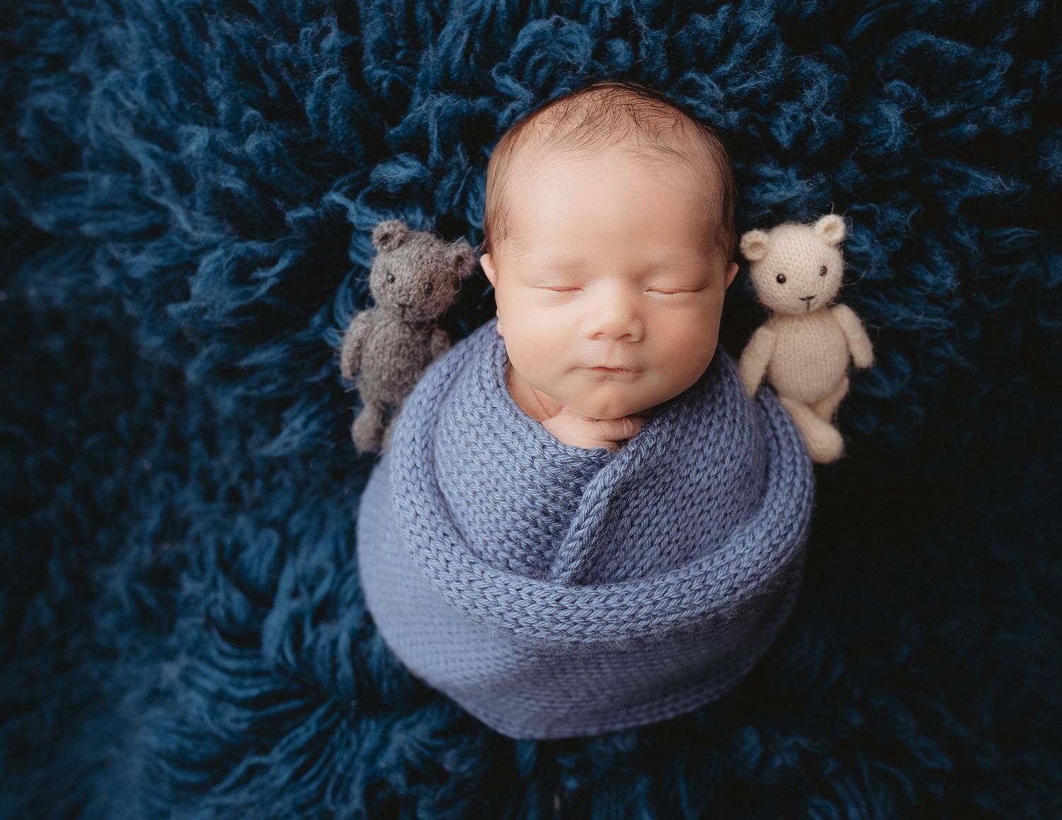 Professional photo of a newborn baby with two small teddy bears