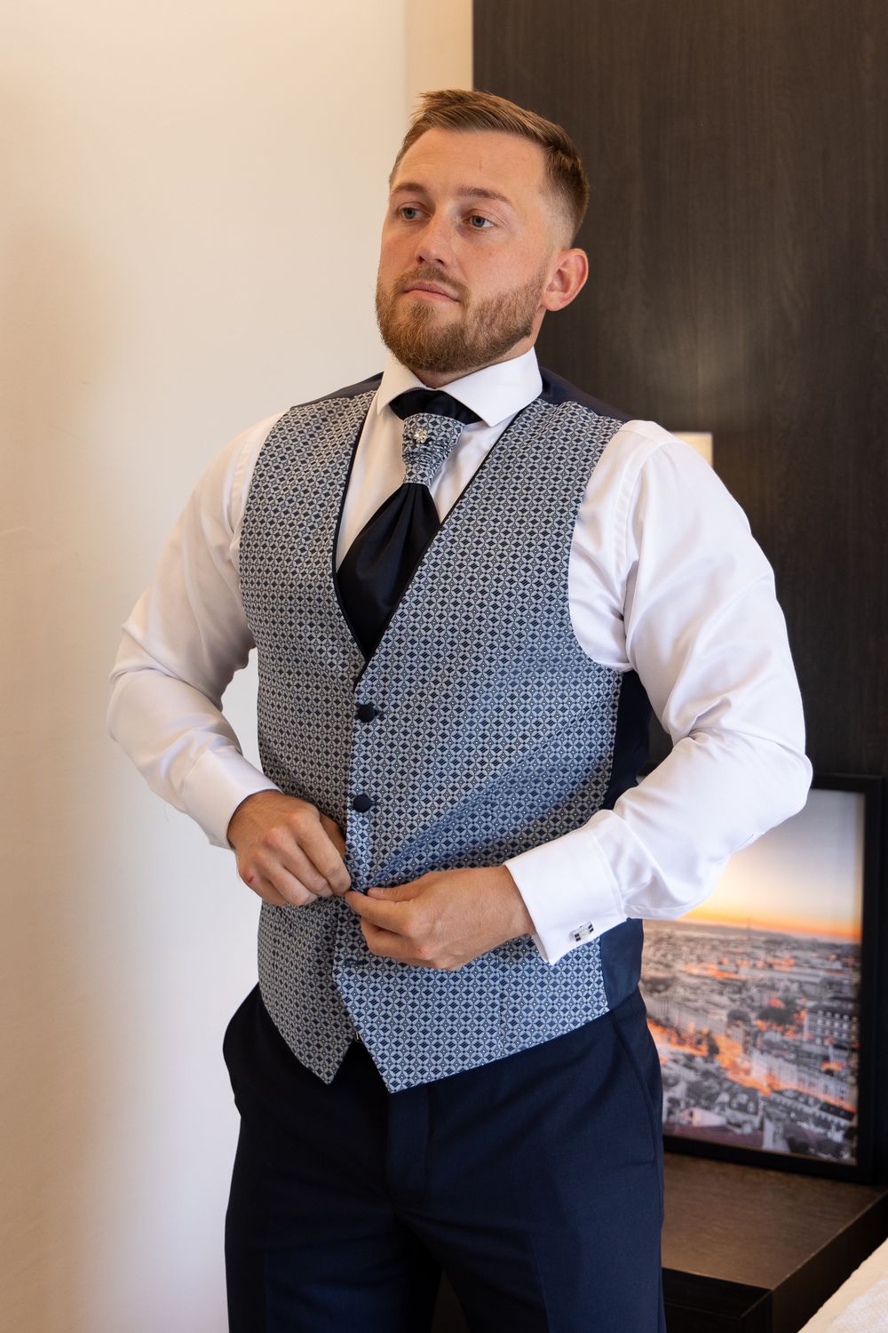Stylish formal attire featuring patterned vest, white shirt and navy tie.