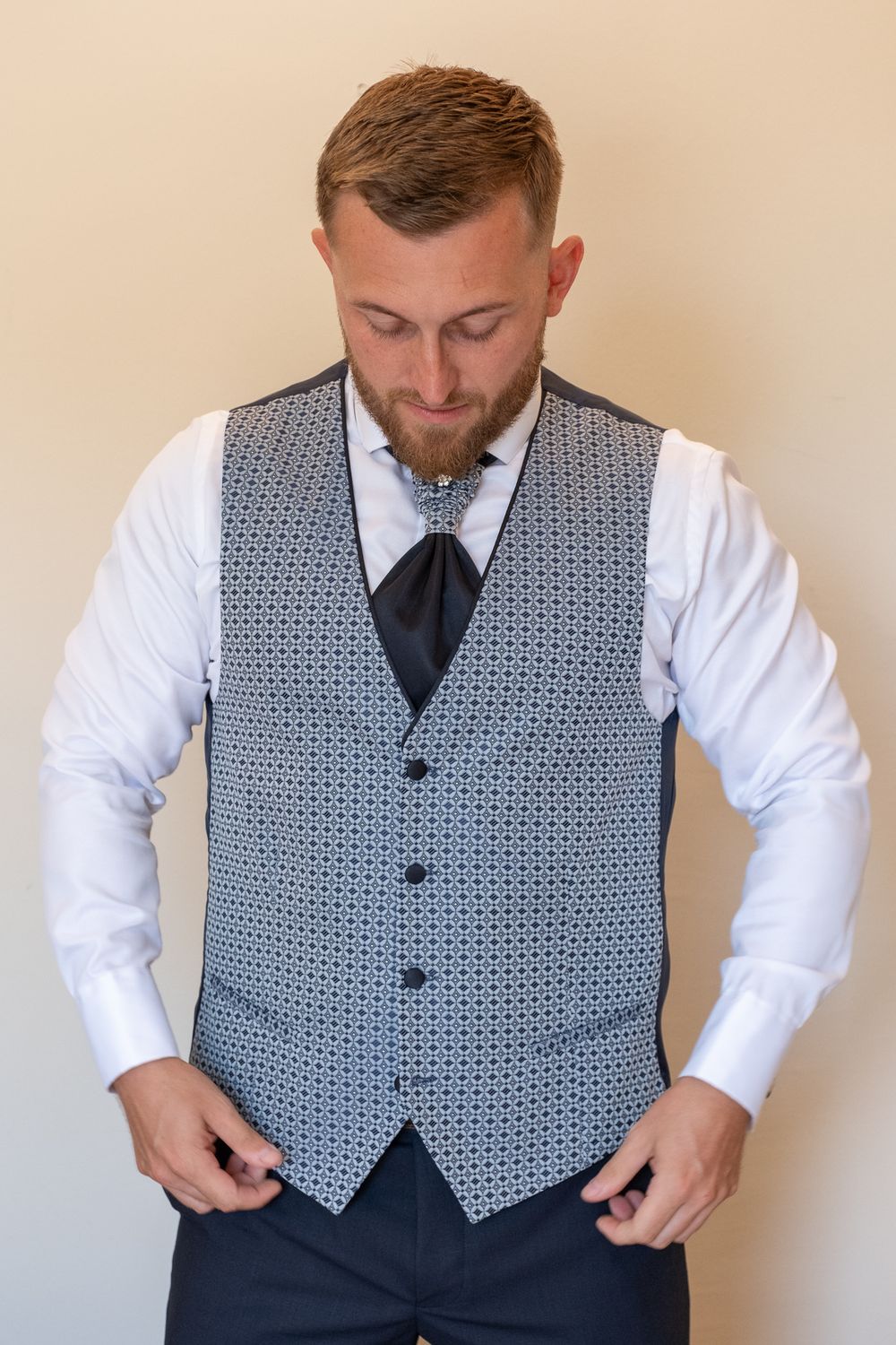 Close-up of patterned grey vest with black tie and white dress shirt.
