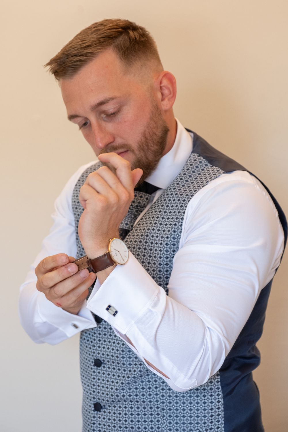 Close-up of dress shirt cuff and wristwatch with patterned vest.