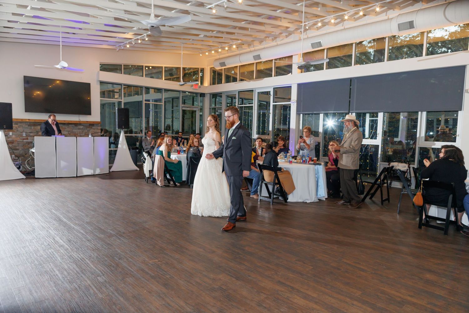 A couple shares a joyful moment at their wedding reception while cutting cake together.