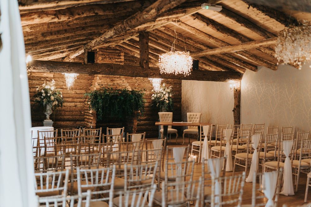 Rustic wooden barn wedding venue with rows of elegant chiavari chairs and crystal chandeliers at Grand Lodge Oaklands.
