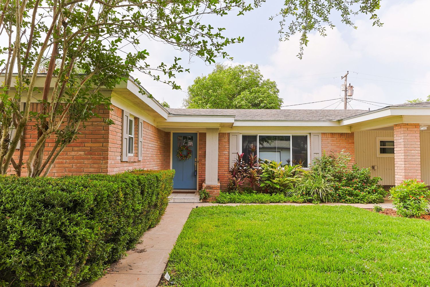 Ranch style residential homes surrounded by green lawns and landscaping on a quiet suburban street.