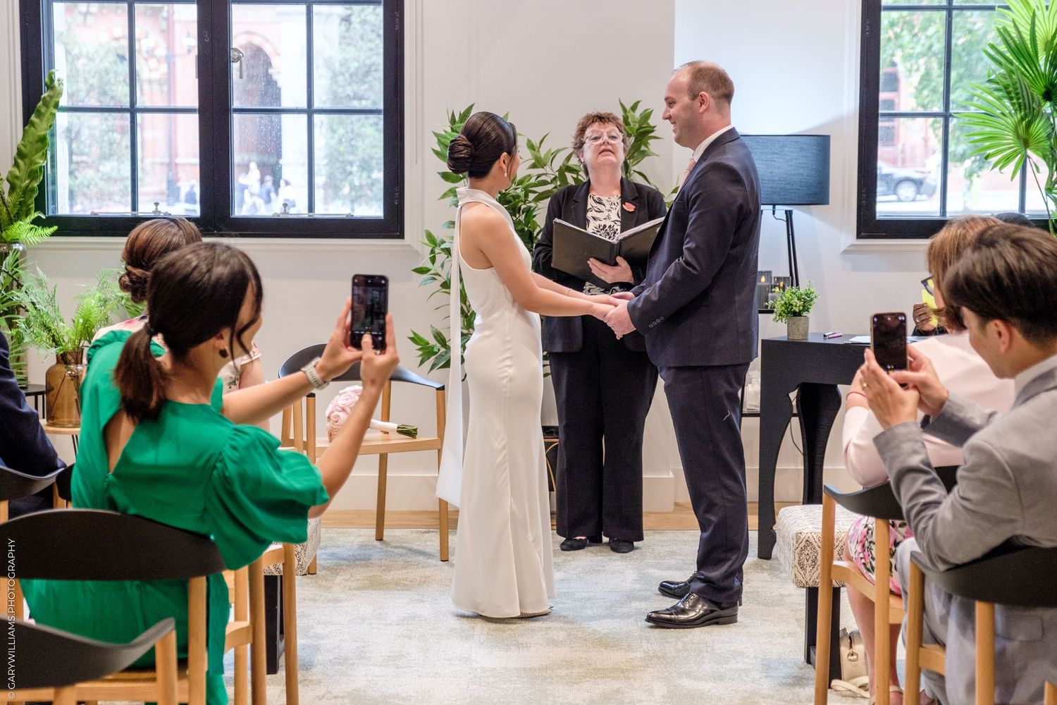 A sequence of wedding ceremony photos showing the couple exchanging vows in front of friends in a bright indoor space.
