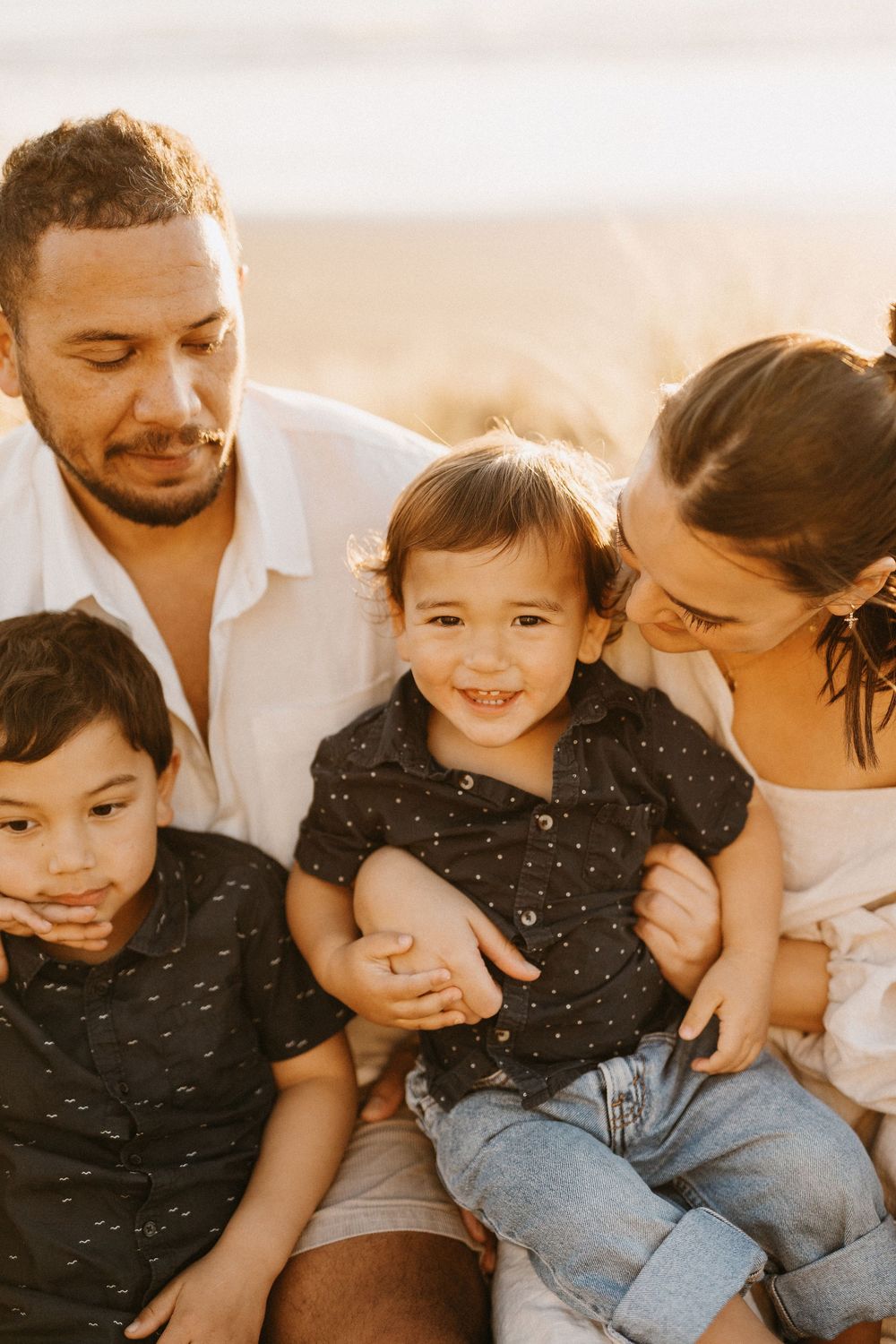 A happy family shares an intimate moment together outdoors during golden hour.
