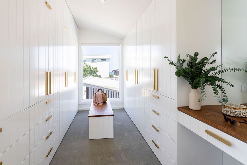 Modern white kitchen cabinets with brass hardware and vertical lines create an elegant and minimalist aesthetic.