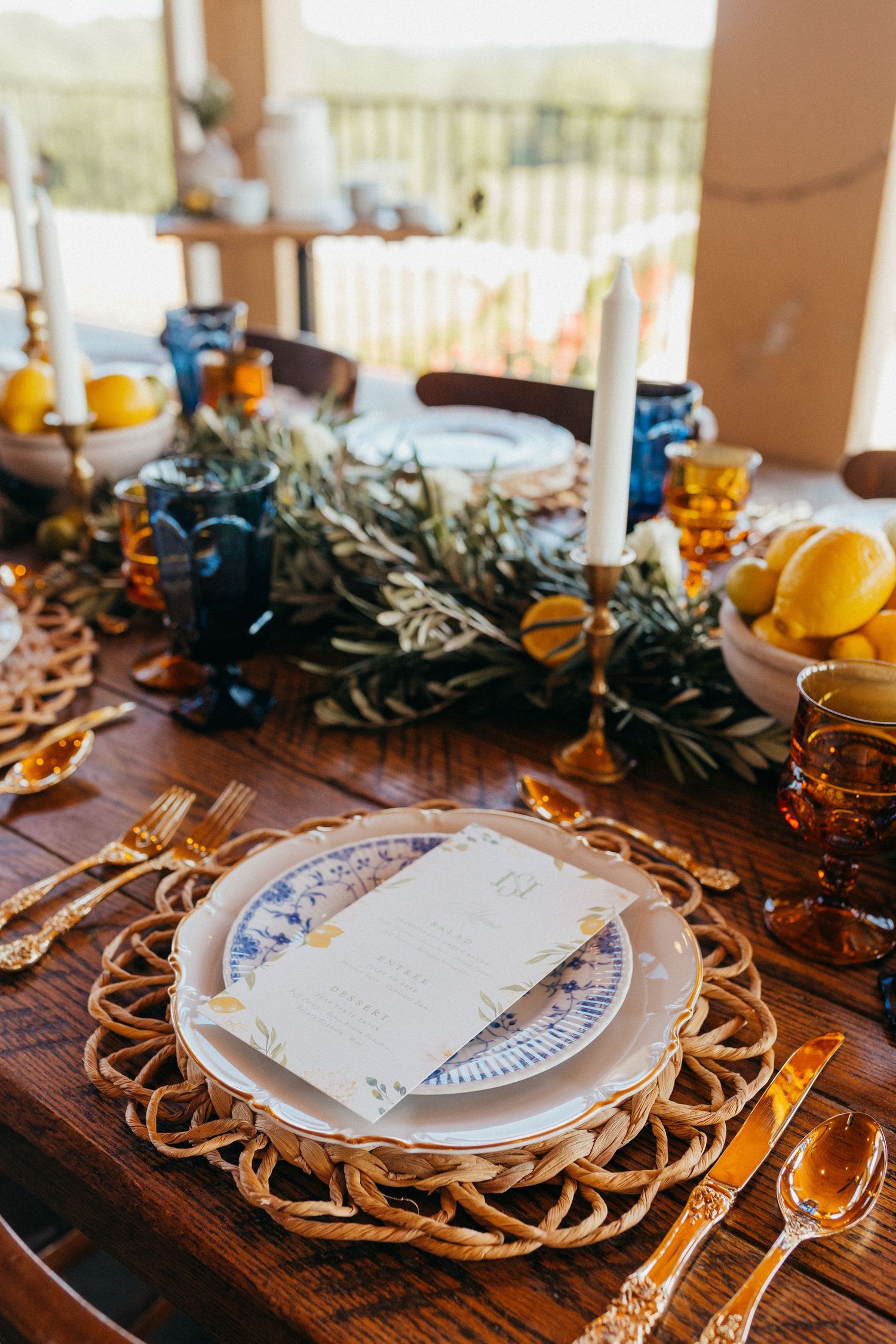 Romantic table setting with ornate gold charger plates, white dishes, and citrus decorations on a rustic wooden table.