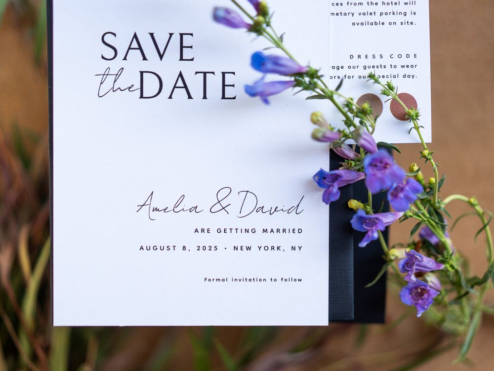 Elegant save the date wedding invitations styled with delicate purple wildflowers against a neutral background.