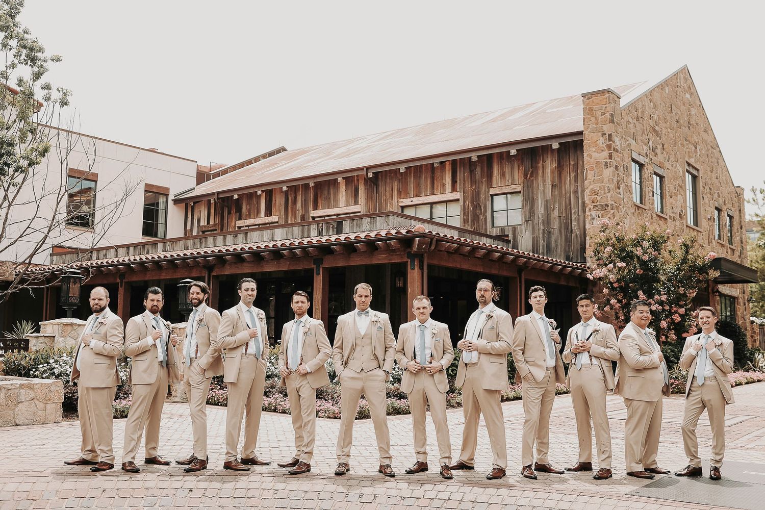 Large Groomsmen Wedding party wearing beige suits and powder blue ties pose in front of the fort worth stockyards