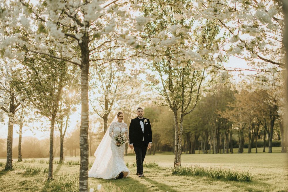 A romantic wedding couple walks through a scenic birch tree grove at Laceby Manor - image captured by Grimsby photographers.