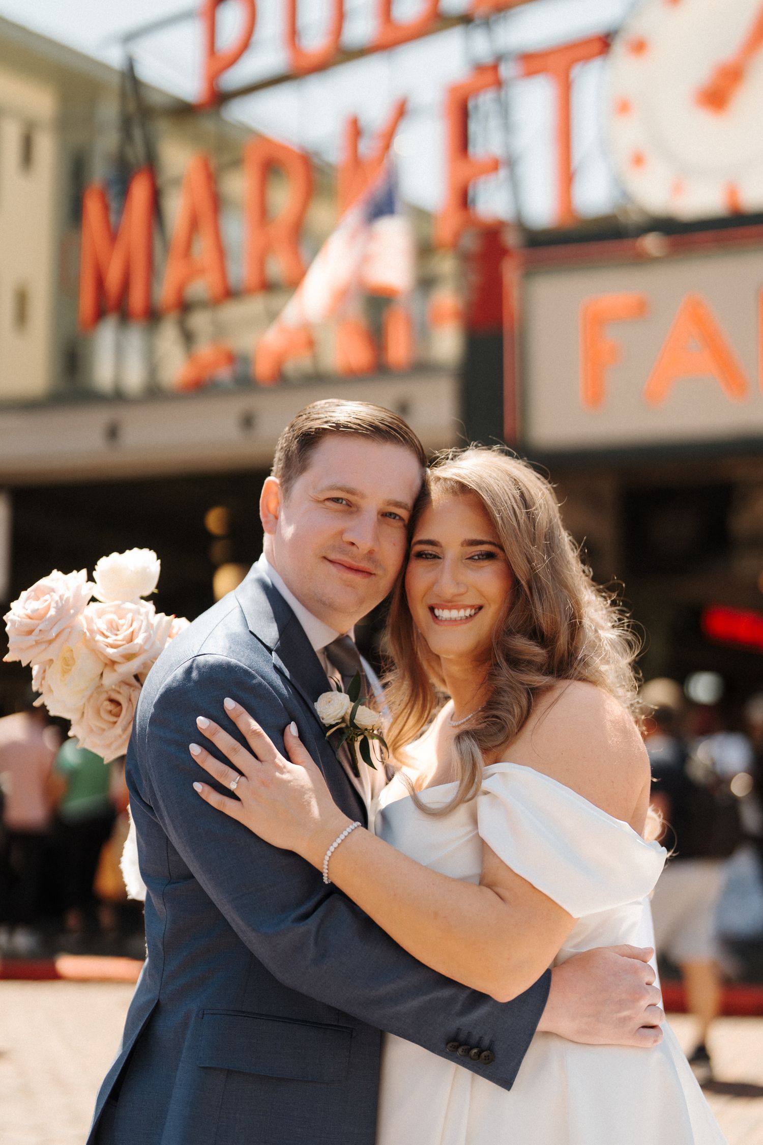 A happy couple embraces outside Pike Place Market in Seattle during their wedding celebration.