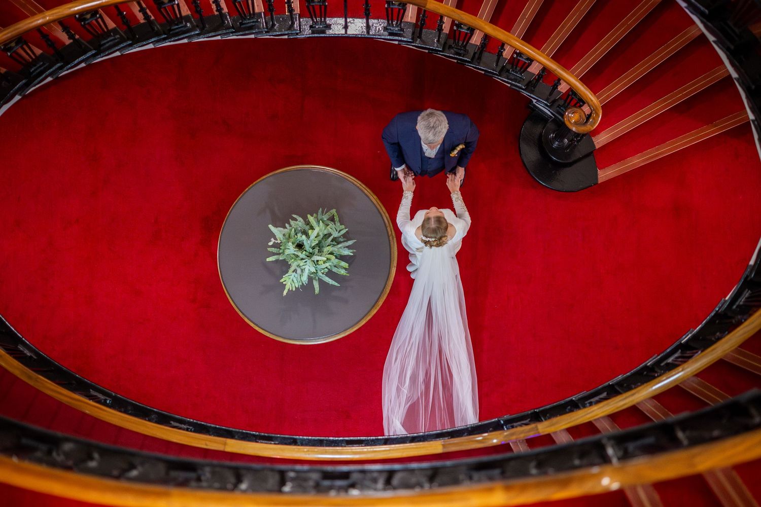 bride and groom standing at the bottom of the staircase holding hands in the Athenaeum foyer Liverpool City Centre wedding reception venue.