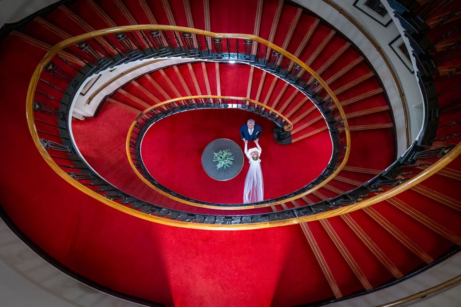 shot down from the the top of the top of the staircase the bride and groom hold hands for a relaxed portrait. Stuart Morris Photography