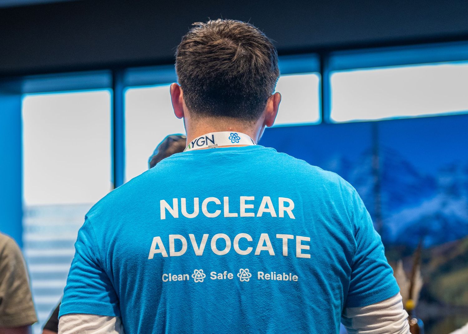 Back view of person wearing blue Nuclear Advocate t-shirt with safety message.