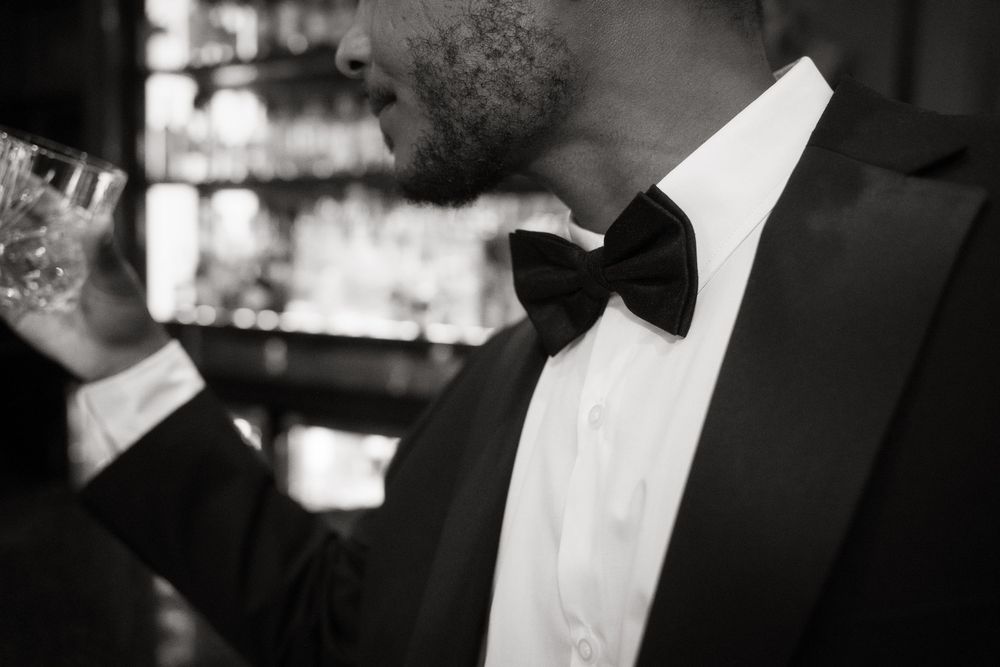 Black and white close-up of a formal tuxedo with bow tie and smoke against blurred background.