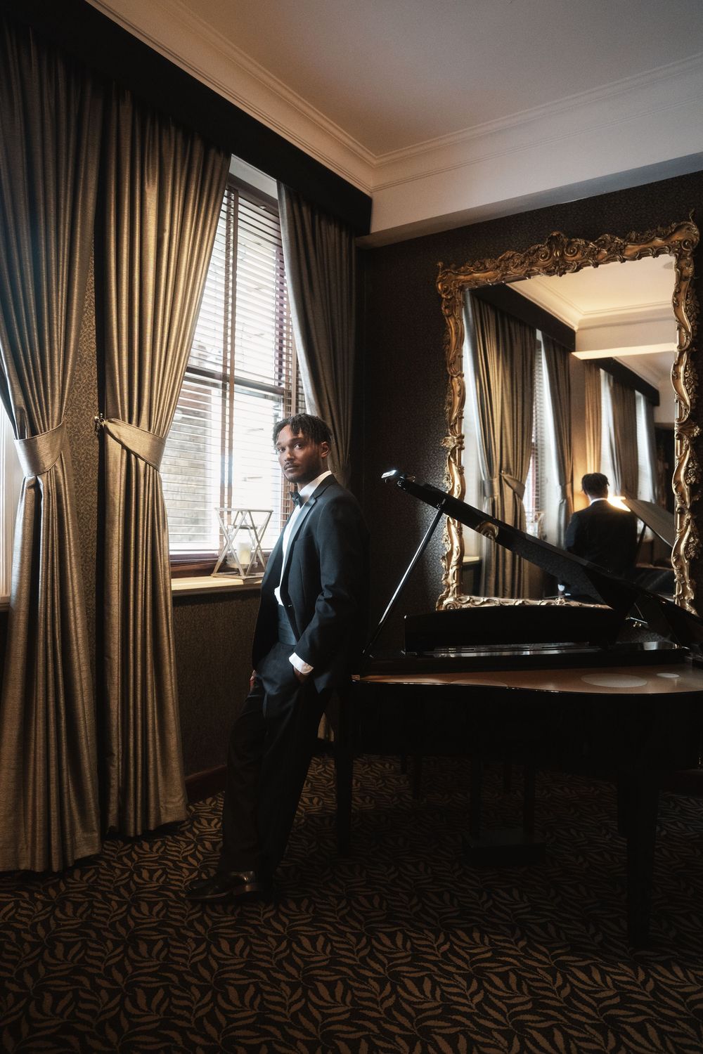 Elegant room with luxurious curtains, grand piano, and ornate mirror reflecting warm natural light from tall windows.
