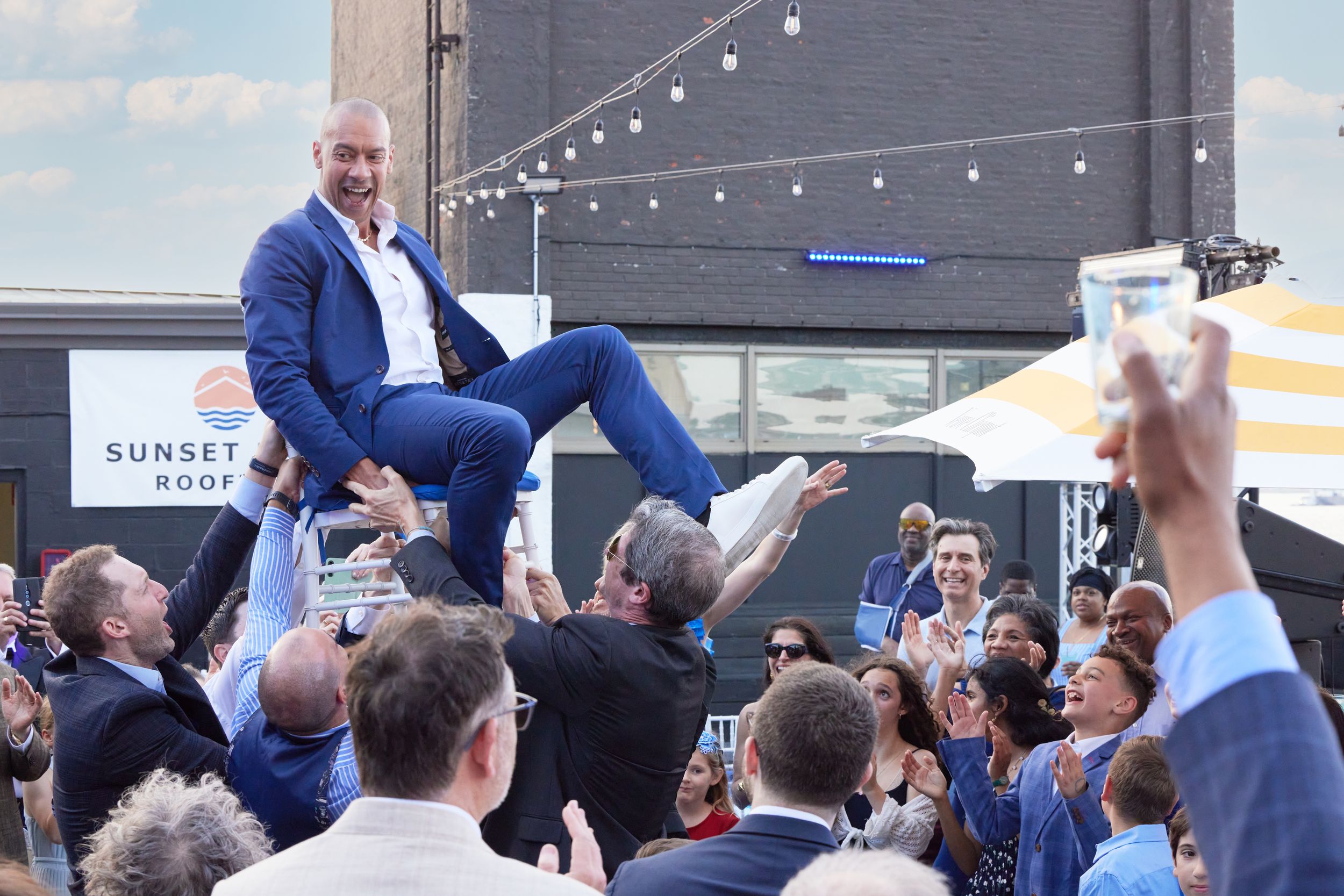 Father lifted during the Hora at Brooklyn Bat Mitzvah at Sunset Park Rooftop. A powerful moment of tradition by George Robert Photography.