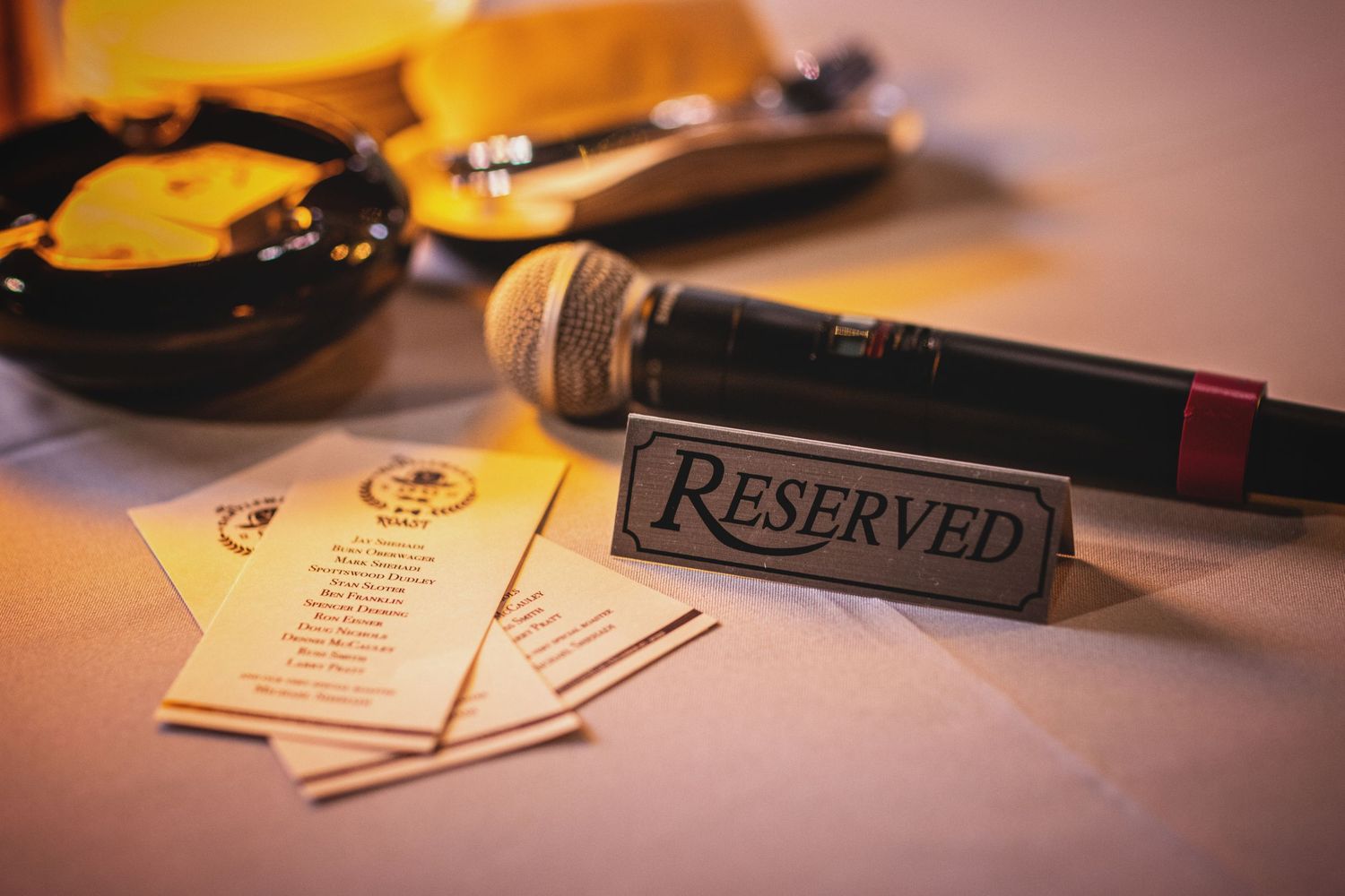 Close-up of reserved table setting with menu and writing instruments in warm lighting.