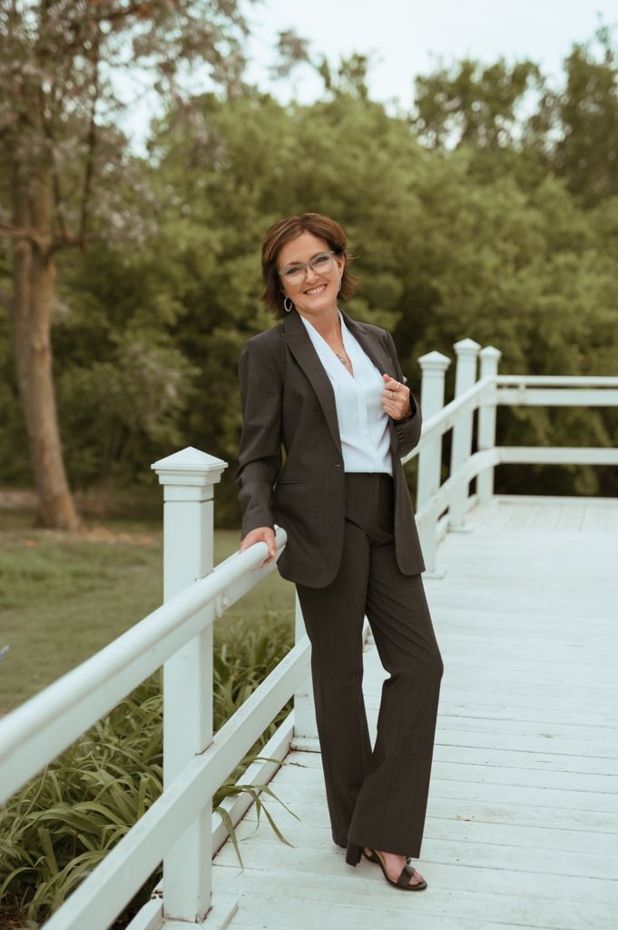 Professional photoshoot on a white bridge boardwalk featuring a sleek black business suit and white blouse in an outdoor setting.