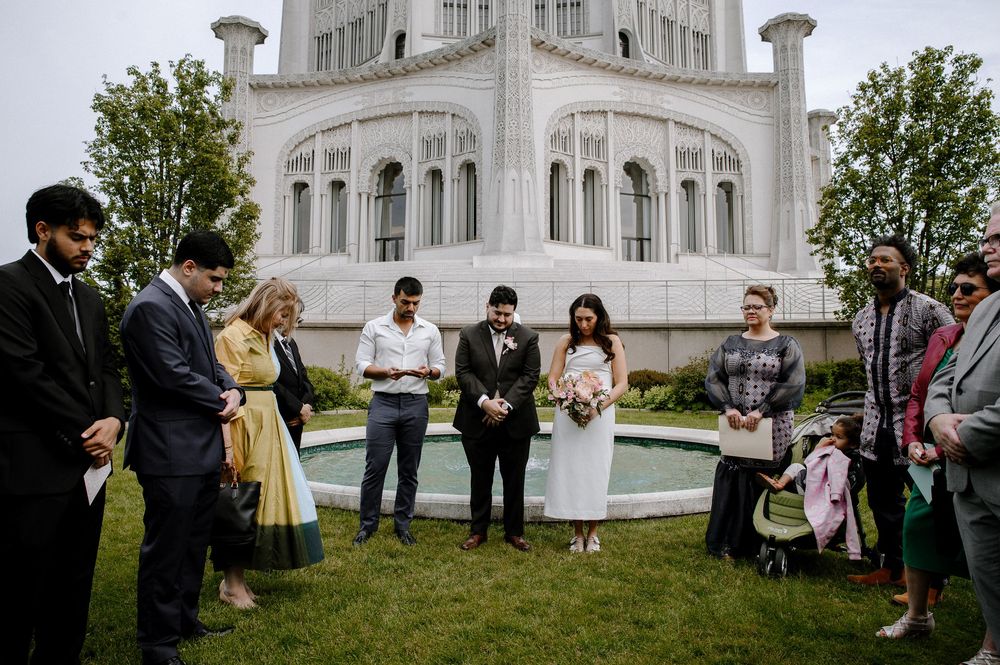 A small outdoor wedding ceremony takes place on the lawn in front of the ornate white Bahai Temple in Wilmette, Illinois.