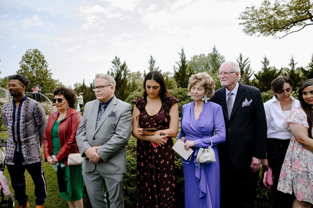 Group of guests standing in line outdoors during a summer celebration event in a garden setting.