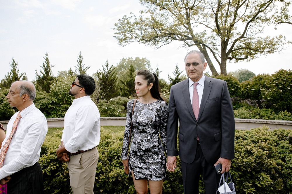 A group of people in formal attire standing in a landscaped garden area.