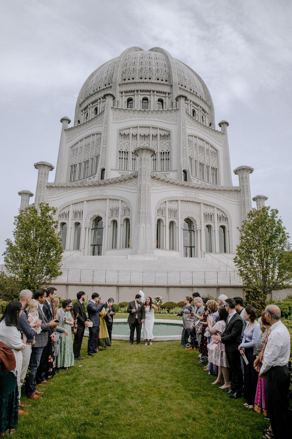 A grand white domed Baha'i Temple with gathering of visitors on the lawn in Wilmette, Illinois.