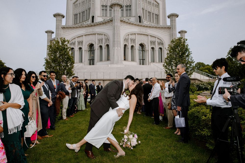 Wedding guests gather outside beautiful white Baha'i Temple in Chicago during outdoor celebration ceremony.
