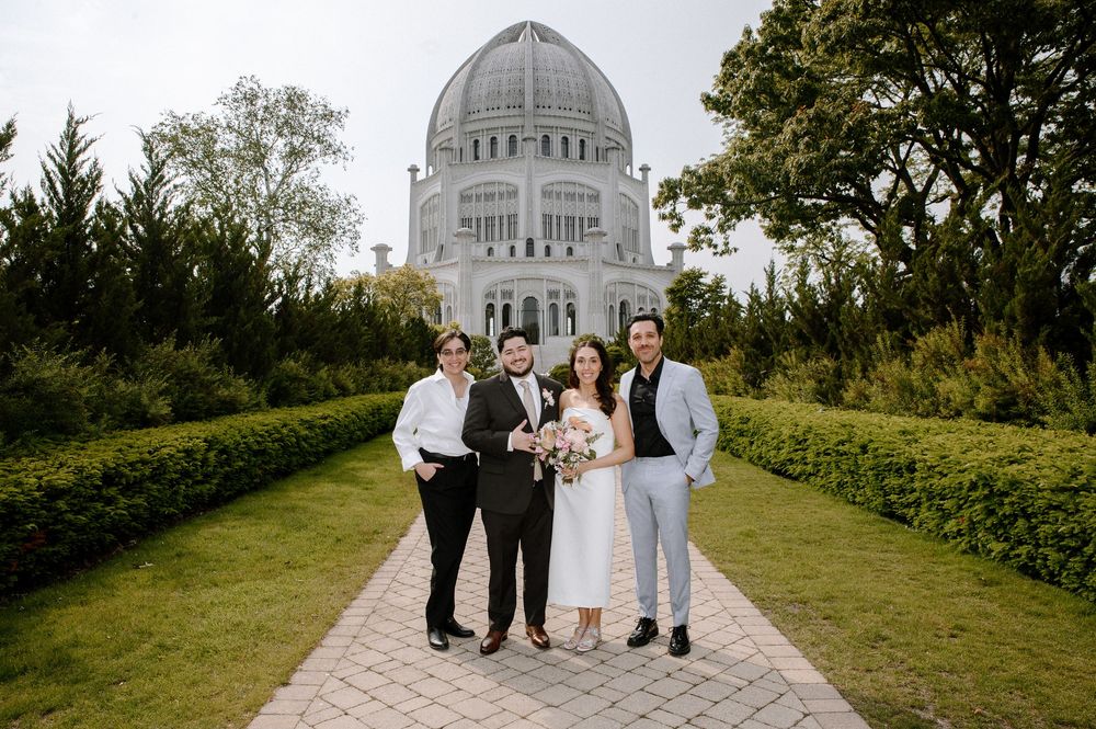 A wedding party stands on a stone path leading to the Bahai Temple in Wilmette, Illinois with its large domed structure visible.