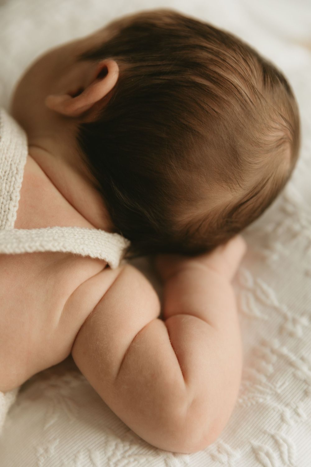 Close-up shots showing delicate details of a sleeping baby resting on textured white fabric in a soft-focused sequence.