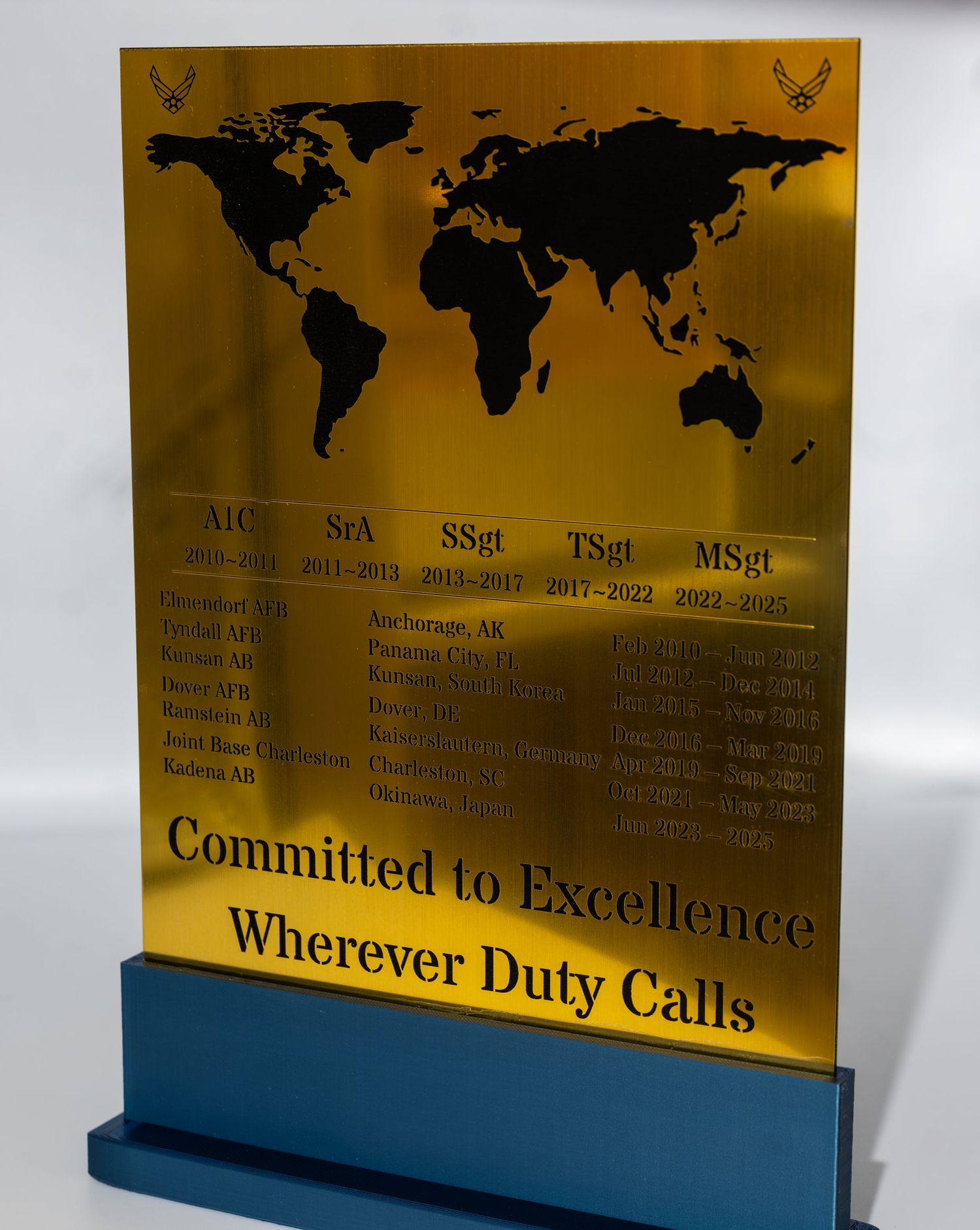 Gold plaque with world map showing military excellence and duty locations.