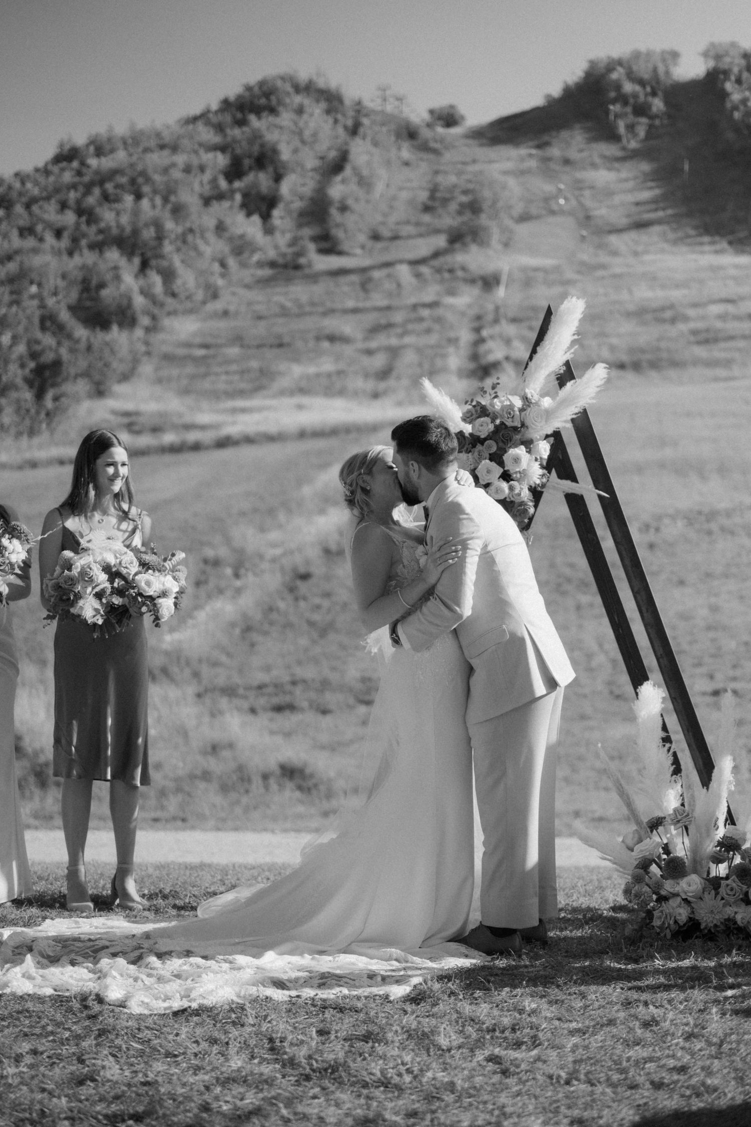 Wedding party taking photos outdoors against a scenic hillside backdrop.