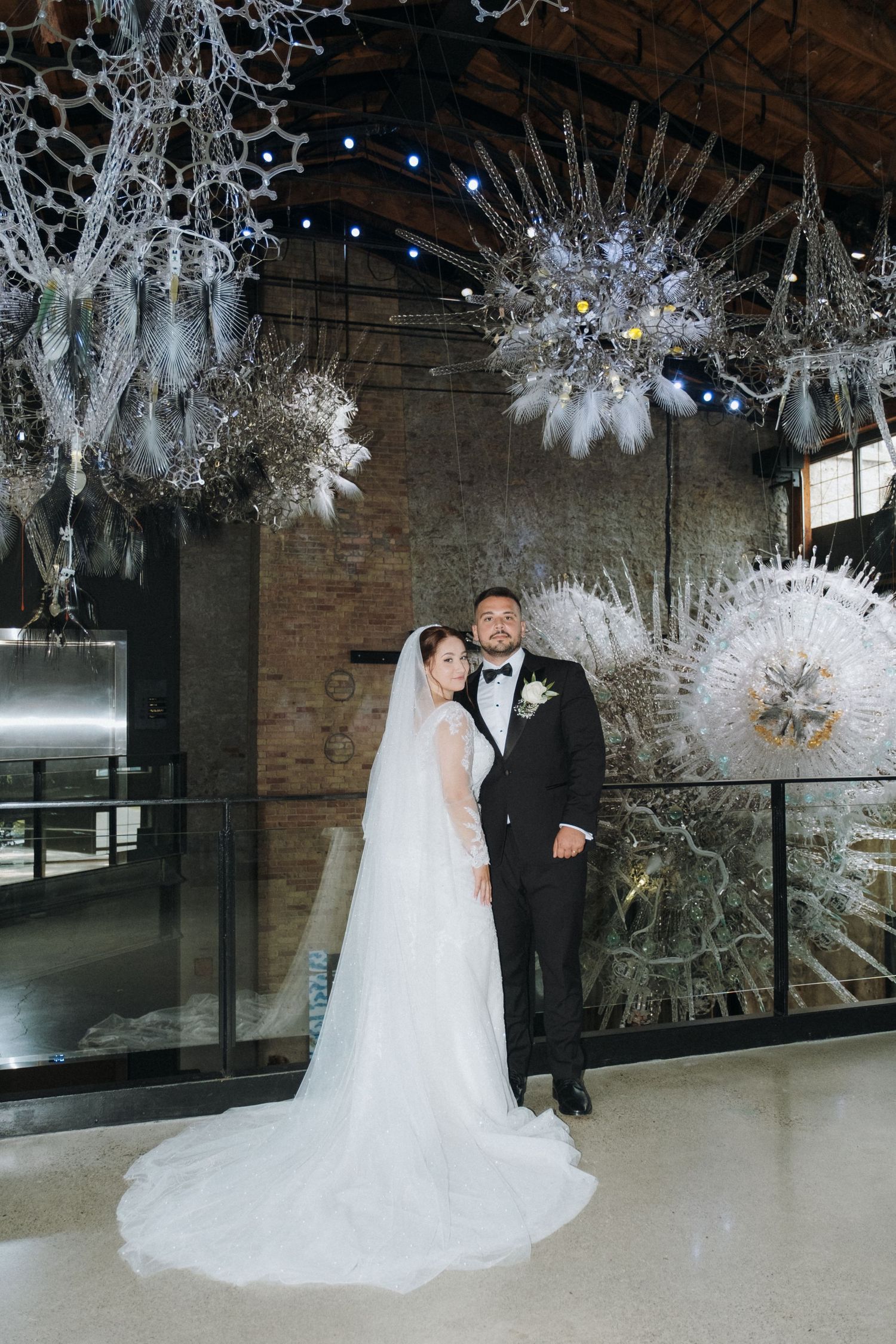 Wedding couple posing under dramatic white starburst decorations in industrial venue.